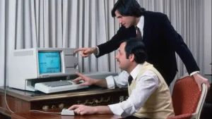 عکس کامپیوتر لیزا روی میز، استیو جابز و جان کاناپه در جلو هستند