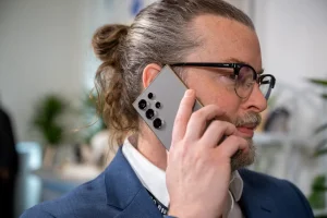 شخصی که با Samsung Galaxy S24 Ultra تماس تلفنی می گیرد و دوربین های پشتی آن را نشان می دهد.