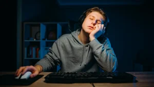 یک گیمر بی حوصله و خواب آلود که پشت میز آنها نشسته است.