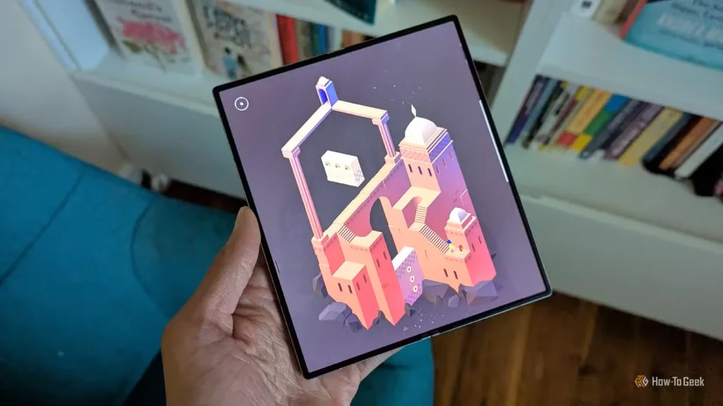  Monument Valley 2 در Galaxy Z Fold 6 با کتاب‌ها در پس‌زمینه.