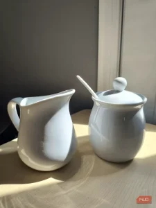 یک لیوان روی یک نرده چوبی با خورشید و آسمان آبی پشت آن - HDR فعال است