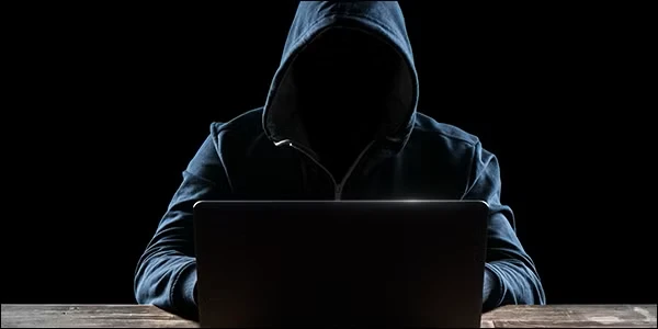 مرد مرموز و خرخون با هودی که لپ‌تاپ را هک می‌کند