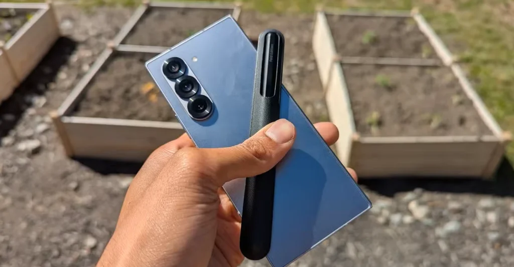 یک گلکسی Z فولد ۶ با قلم S Pen در مقابل یک باغ.