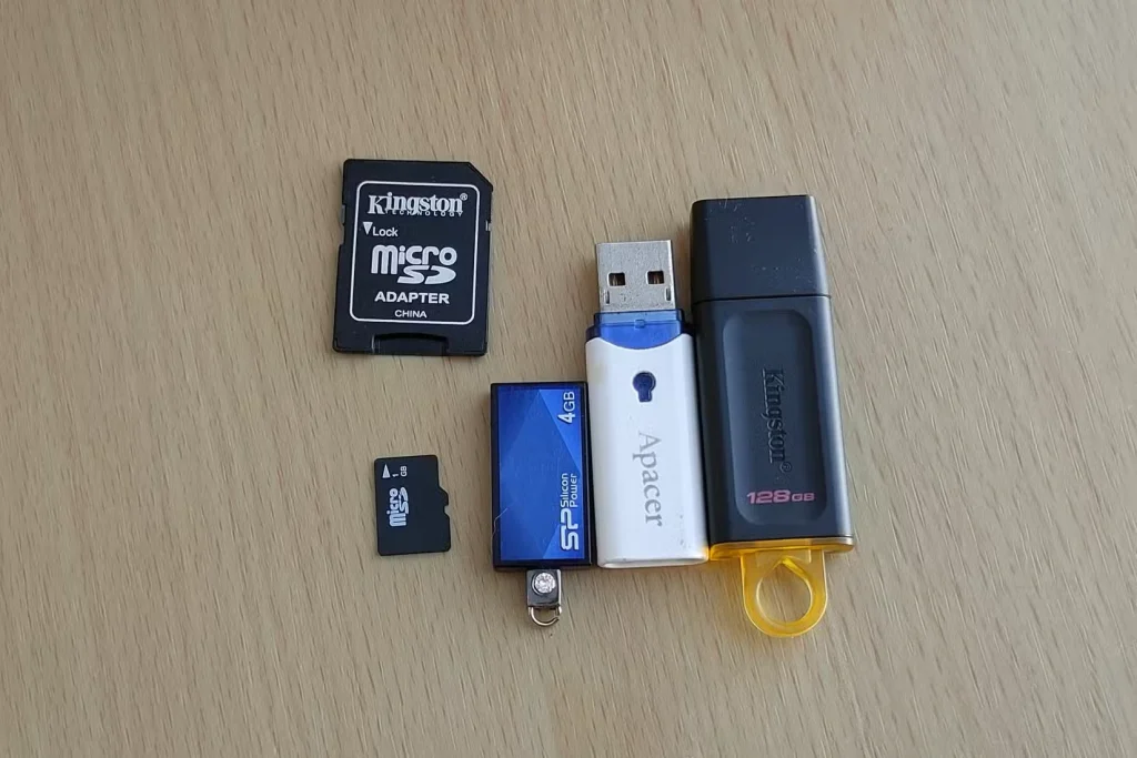 یک کارت microSD و آداپتور کارت SD در کنار سه فلش درایو USB مختلف.