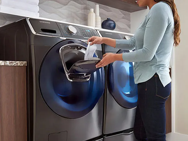 خانمی درحال انداختن لباس داخل ماشین لباسشویی